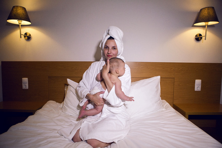 mother in a bathrobe lying on bed with sonの写真素材