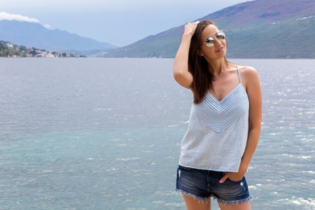 girl in denim shorts is standing with his back against the background of the Bay in Montenegroの写真素材