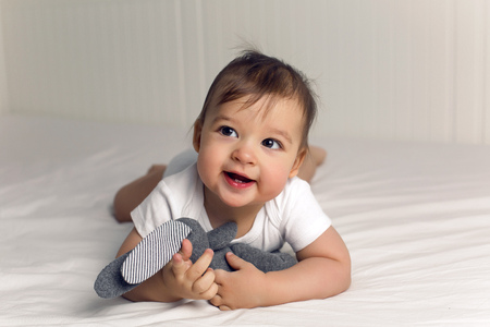 boy baby t-shirt lies under a blanket in a big white bed