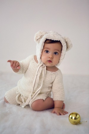 child of eight months sitting in the studio in a hat with bear earsの写真素材