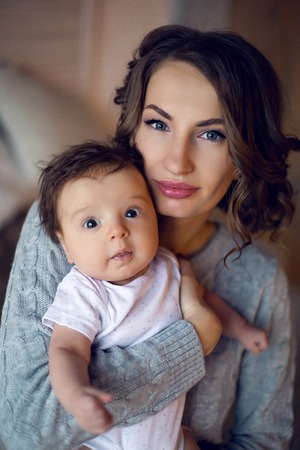 mom in a sweater holding in his hand his sons babyの写真素材