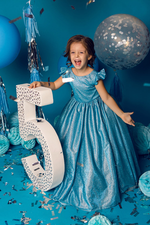 girl in the blue dress in the Studio with the balloon and with the number fiveの写真素材