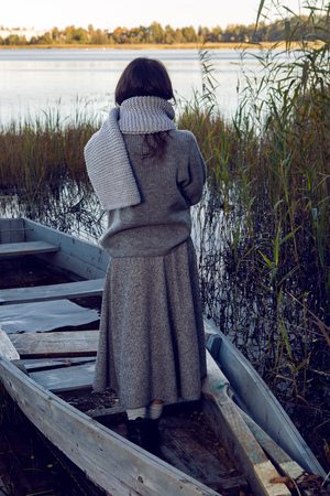 woman stands back sweater and skirt next to the lake in the fallの写真素材