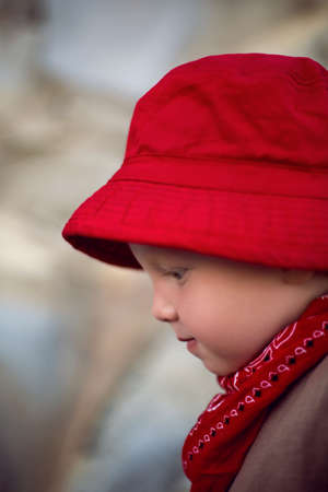 stylish boy child in a vest stands on a pebble beach by the sea in summerの写真素材
