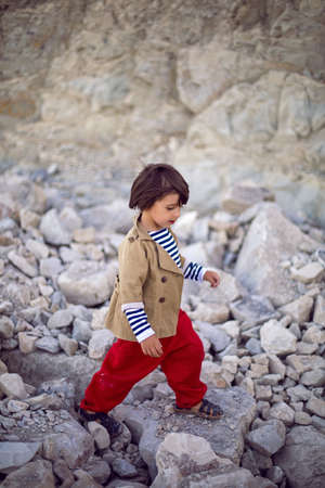 stylish boy sailor in a vest and red pants walk on the seashore in summerの写真素材