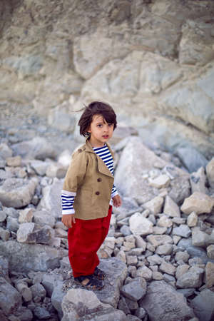 stylish boy sailor in a vest and red pants walk on the seashore in summerの写真素材