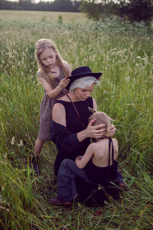 mother in an evening dress and a retro camera with two daughters on a green field with grass in the summerの写真素材