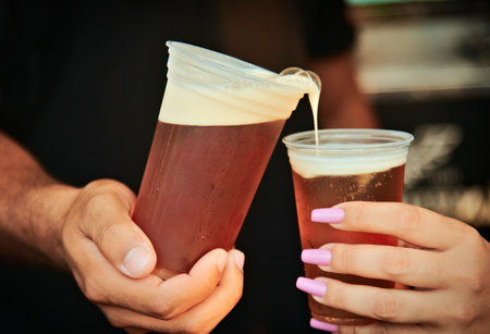 Hands holding disposable beer cups and sharing the drink, at festival.