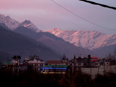 Pink Sky with snow-covered mountains Glacier and tall trees in Himachal Pradesh Indiaの写真素材