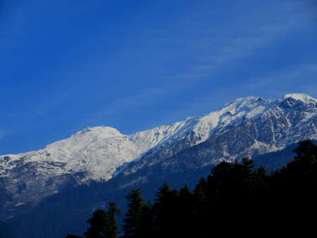Dark blue Sky with snow-covered mountains and trees in Himachal Pradesh Indiaの写真素材