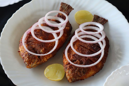 Deliciously prepared traditional South Indian fish fry served on a white plate, garnished with raw onion rings and lemon wedges. Captured in Munnar, this image showcases regional Kerala cuisine, emphasizing crispy texture and local flavorsの写真素材