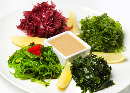 Plate with salad Chuka Seaweed with lemon and peanut sauce on an isolated white backgroundの写真素材