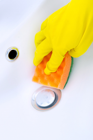 woman doing chores in bathroom at home cleaning sink and faucet with spray detergentの写真素材