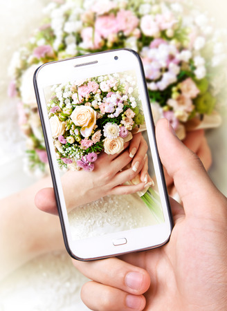 Hands taking photo Bridal Bouquet with smartphone
