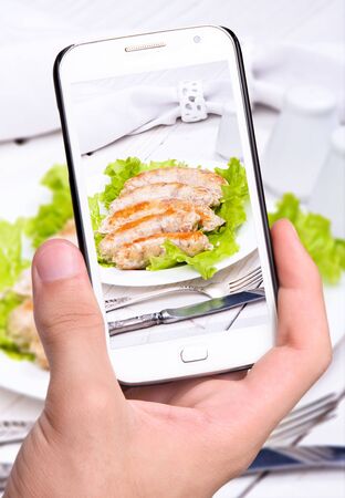 Hands taking photo sausage with smartphoneの写真素材