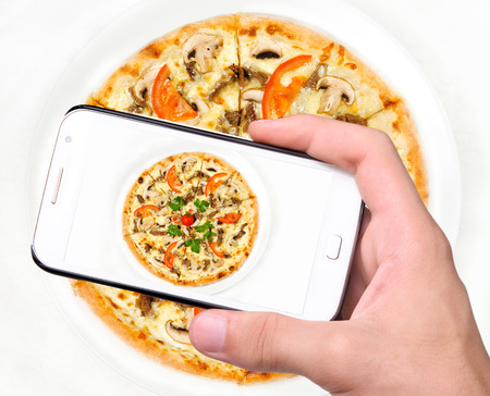 Hands taking photo pizza with smartphoneの写真素材