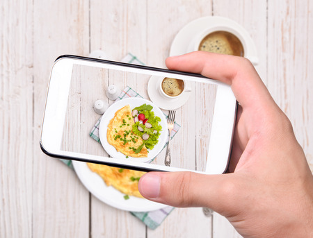 Hands taking photo egg omelette with smartphoneの写真素材