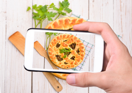 Hands taking photo mushroom pie with smartphoneの写真素材