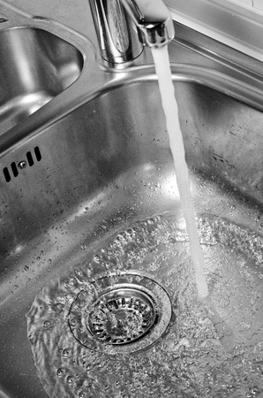 Stainless steel sink plug hole close up with waterの写真素材