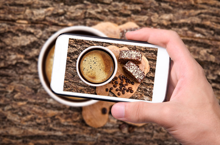 Hands taking photo coffee cup with smartphone.の写真素材