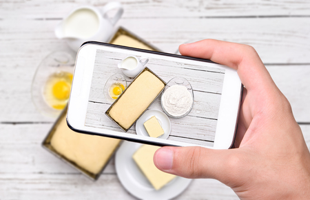 Hands taking photo baking bread with smartphone.の写真素材