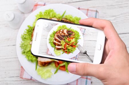 Hands taking photo chicken breast with smartphone.の写真素材