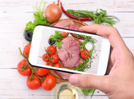 Hands taking photo raw meat with smartphone.の写真素材