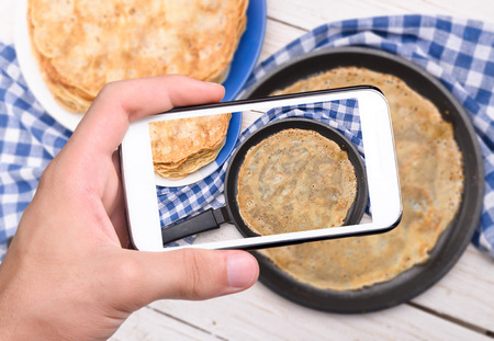 Hands taking photo pancakes with smartphoneの写真素材