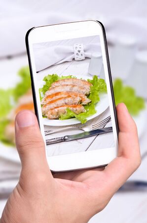 Hands taking photo sausage with smartphoneの写真素材