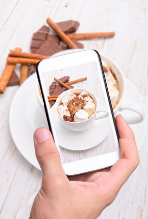 Hands taking photo hot cocoa with smartphone.の写真素材