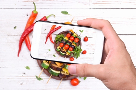 Hands taking photo grilled vegetables. with smartphone.の写真素材