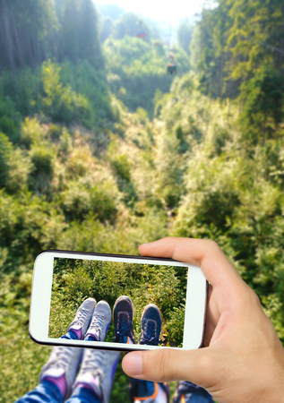 Hands taking photo view of legs with smartphone.の写真素材