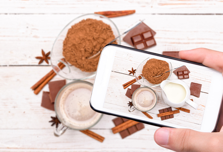 Hands taking photo cup of tasty hot cocoa with smartphone.の写真素材