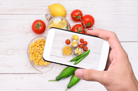 Hands taking photo homemade healthy salad in glass jar with smartphone.の写真素材