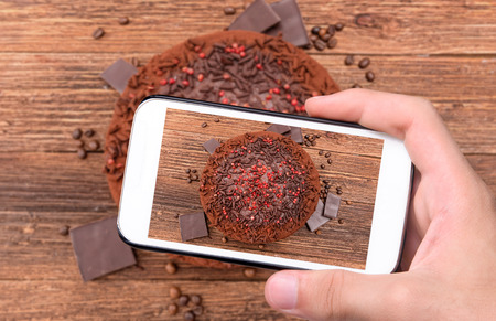 Hands taking photo truffle chocolate cake with smartphone.の写真素材