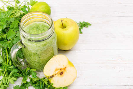 Smoothies with apple, lemon, parsley in glass jars on a wooden background. Concept of cooking.の写真素材