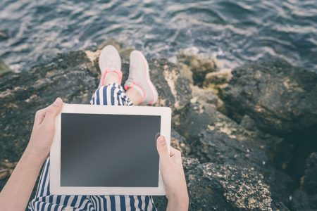 Girl using a digital tablet by the sea.の写真素材