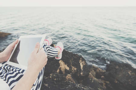 Girl using a digital tablet by the sea.の写真素材