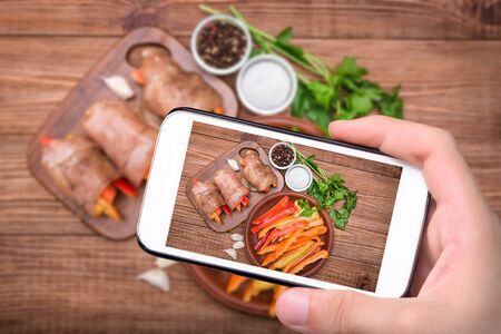 Hands taking photo baked chicken rolls with paprika with smartphone.の写真素材