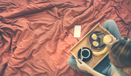 Young woman is having a healthy breakfast in bed.の写真素材
