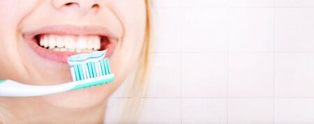 Happy young woman brushing teeth.