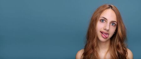 Young woman with pill on her tongue isolated on gray background.の写真素材