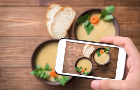 Hands taking photo pea soup with smartphone.の写真素材
