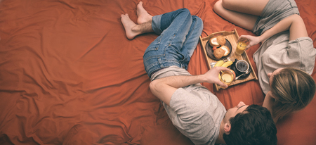 Young couple is lying in bed with dog and having a healthy breakfast.の写真素材