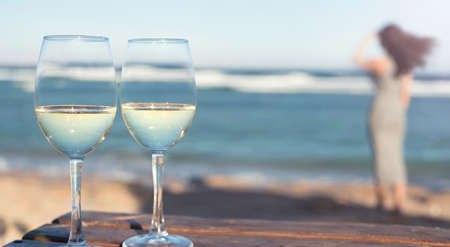 Two white wine wineglasses over sea background. Tropical vacation on beach.の写真素材