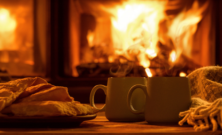 Steam from a cup with a hot cocoa on the fireplace background.の写真素材