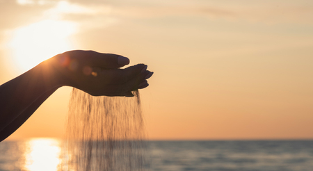 Sand running through a woman's hands.の写真素材
