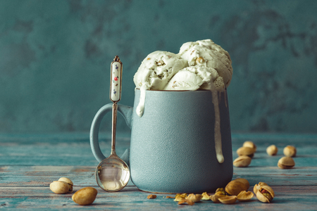 Pistachio ice cream in a cup on a wooden table.の写真素材