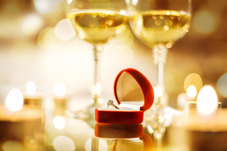 Two wine wineglasses and the red box with engagement ring over bokeh background. Romantic concept.の写真素材