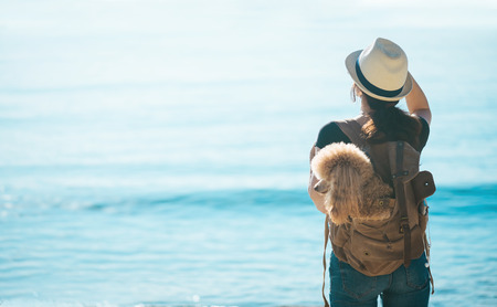 Woman traveler with a dog in the backpack. Concept of travel.